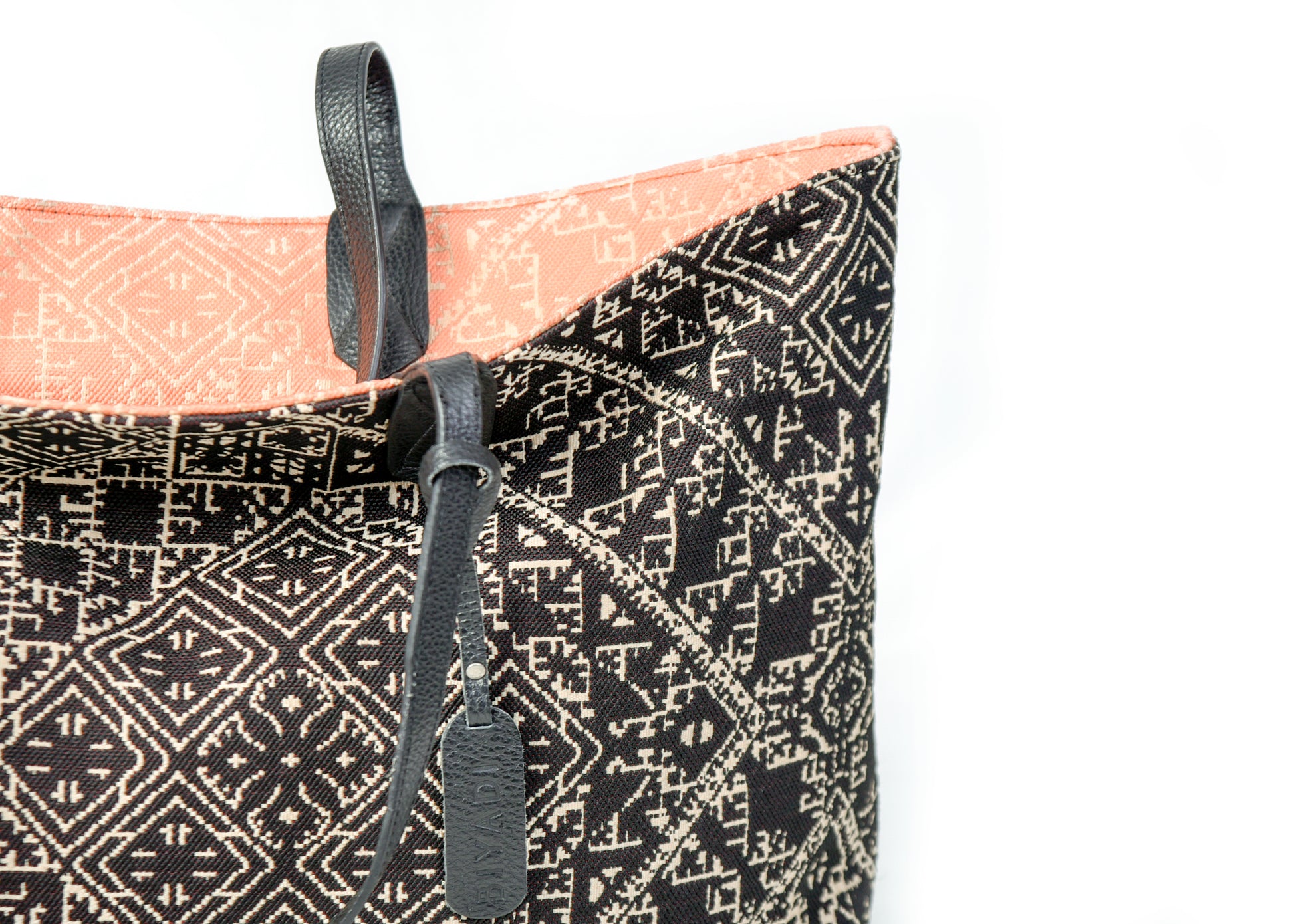Détail du sac cabas reversible noir et corail en tissu marocain tissé avec anse en cuir noir et étiquette en cuir Biyadi Collection.