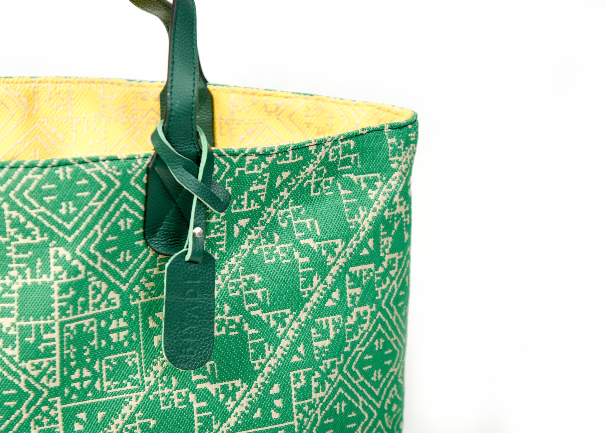 Détail du sac cabas reversible vert et jaune en tissu marocain tissé avec anse en cuir noir et étiquette en cuir Biyadi Collection.