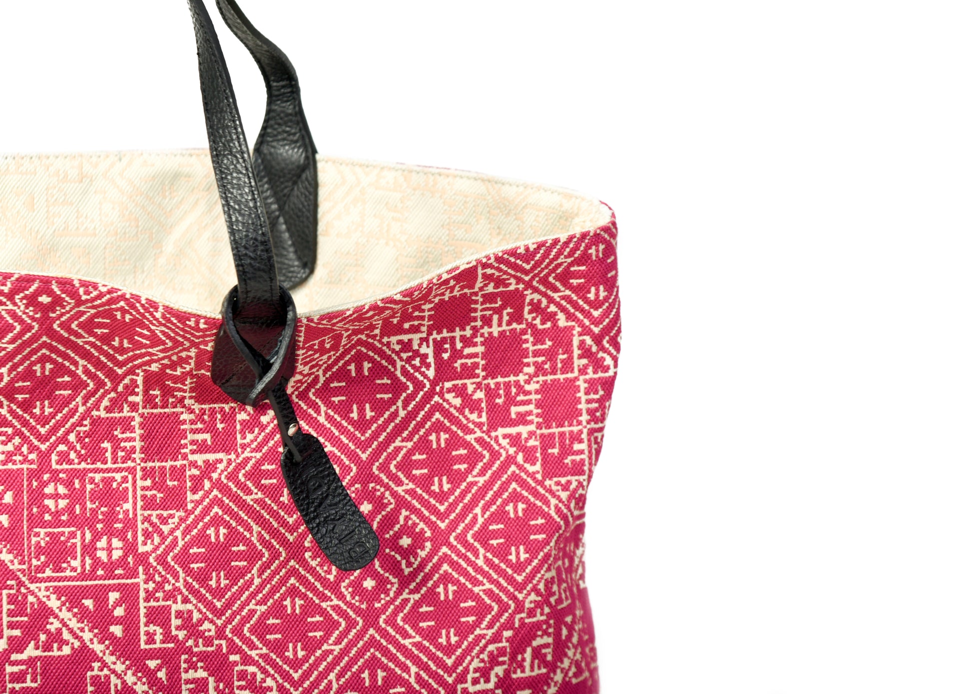 Détail du sac cabas reversible veteau et fushia en tissu marocain tissé avec anse en cuir noir et étiquette en cuir Biyadi Collection.