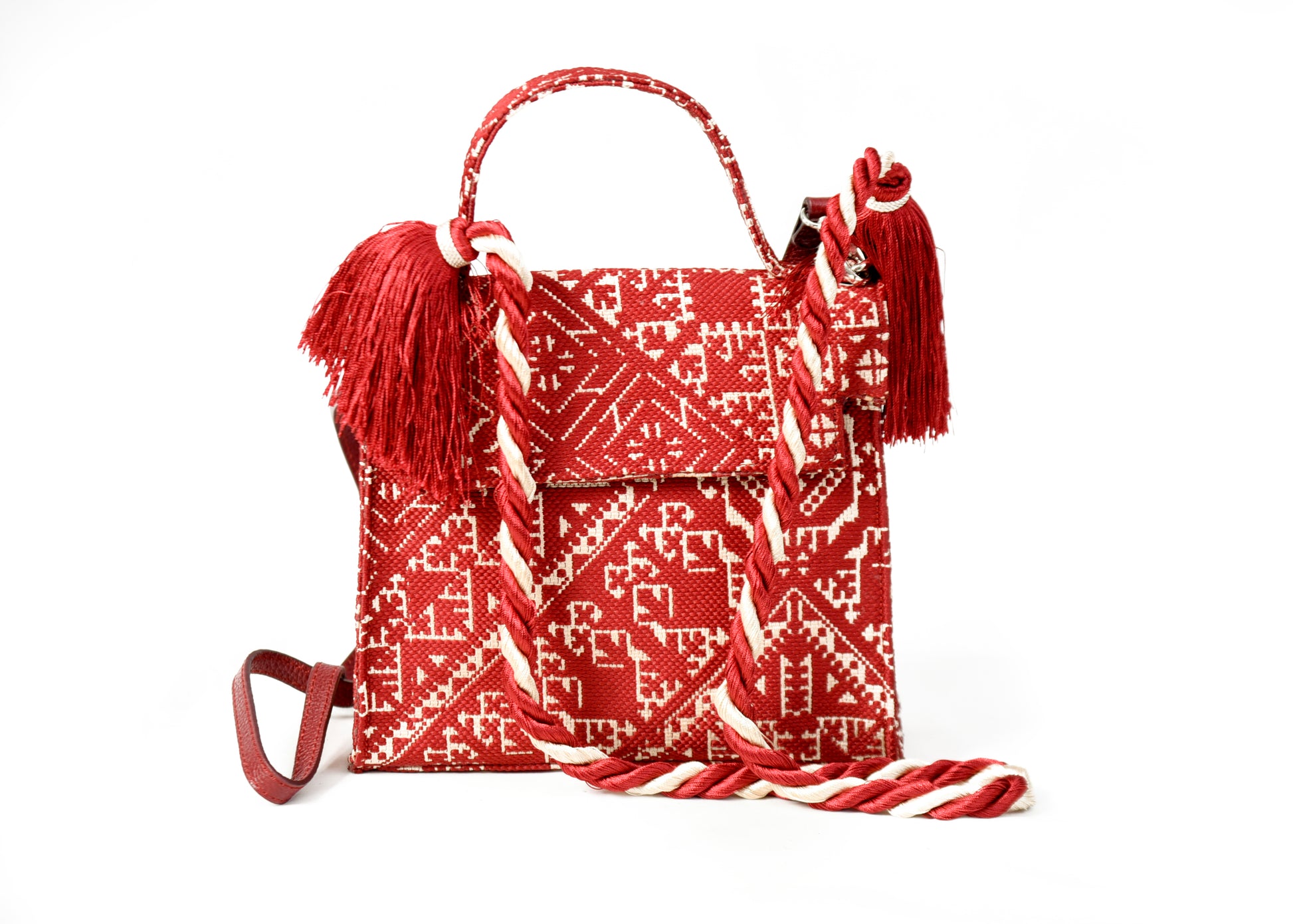 Sac à main bordeau et écru en tissu marocain tissé avec anses tressées, pompons en cuir et bandoulière amovible.