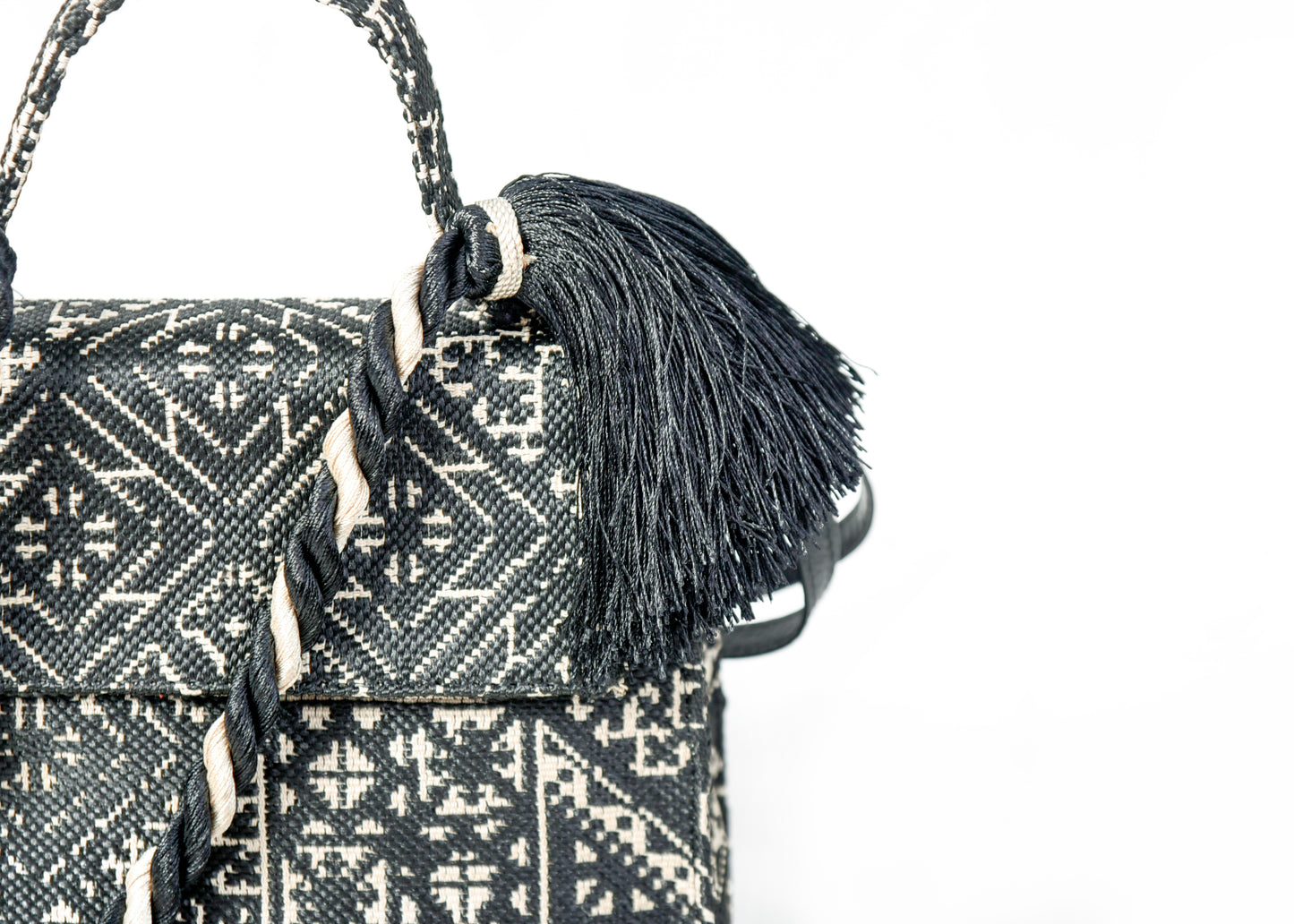 Détail du pompon noir et du tressage décoratif sur un sac à main en tissu marocain noir et écru tissé au Maroc.