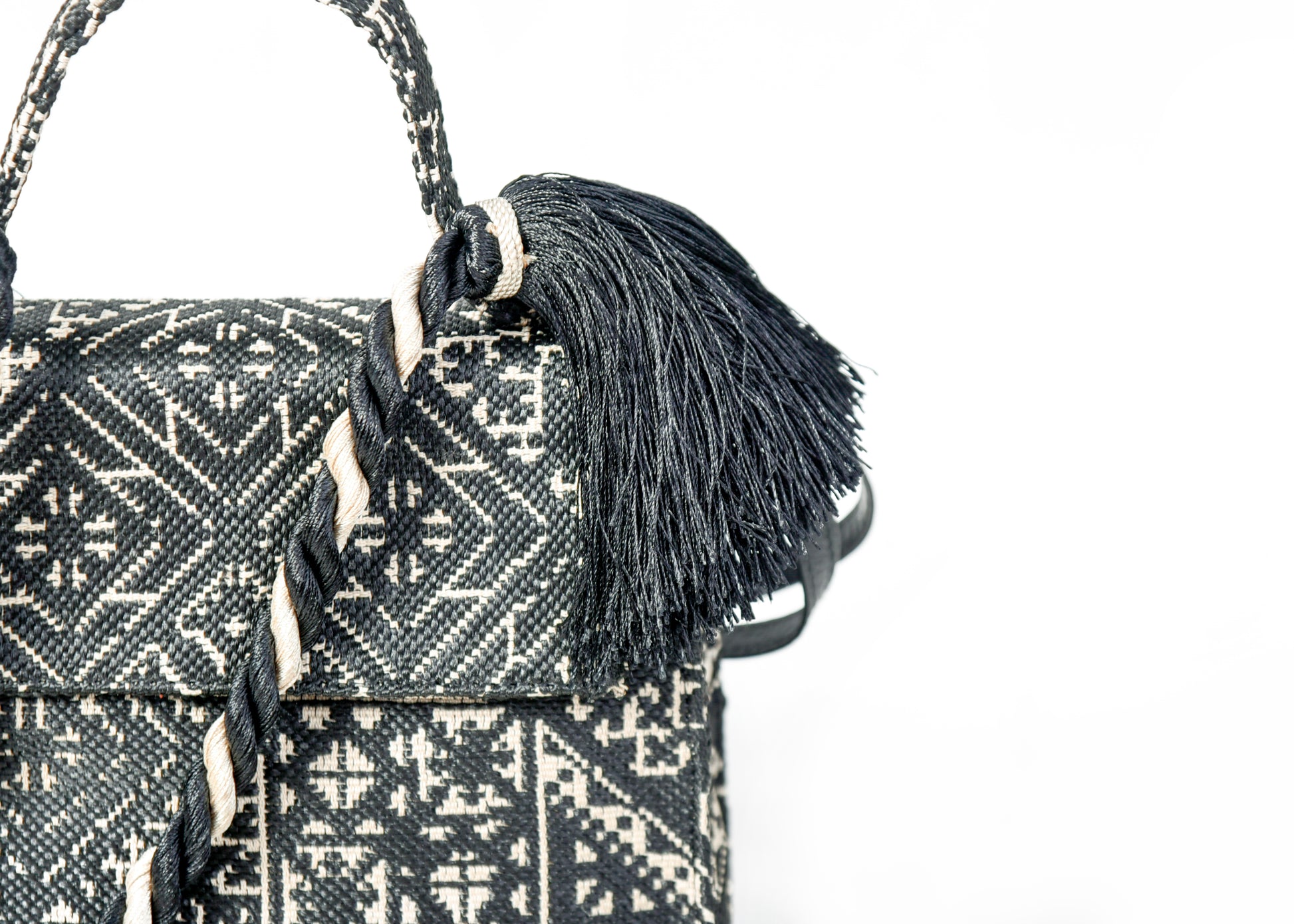 Détail du pompon noir et du tressage décoratif sur un sac à main en tissu marocain noir et écru tissé au Maroc.